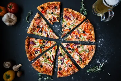 Down Sliced Pizza Topped Black/Dark Wallpaper 4K 5472x3648 Top-down, View, Of, Sliced, Pizza, Topped, With, Capsicum, Pepper, Olives, Accompanied, Glass, Orange, Gray, Landscape, 4k