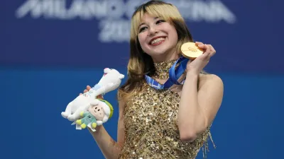 Smiling Female Figure Skater Holding Nature Wallpaper 4K 2560x1440 Smiling, Female, Figure, Skater, Holding, A, Gold, Medal, Plush, Mascot, Winter, Olympics, Brown, White, Gray, Ultrawide, QHD